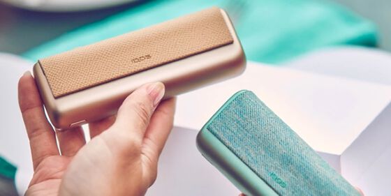 Hands holding IQOS ILUMA PRIME Pocket Chargers.