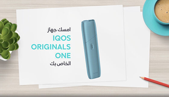 جهاز التبغ المُسخَّن IQOS ORIGINALS ONE بلون التركواز بجانب كابل شحن.