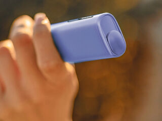 Hands holding an unopened IQOS device box.