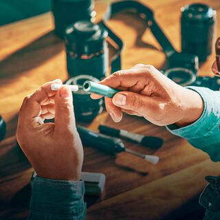 صورة مقربة لمصور يدخل لفافة التبغ المسخّن في جهاز IQOS.