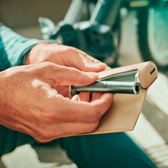 A person with a Jade Green IQOS ILUMA PRIME Holder and Pocket Charger in a full wrap.