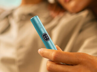 A hand showing an IQOS device to another person.