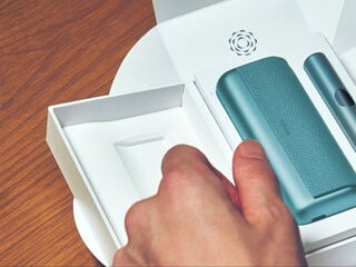 A person holding an unopened IQOS device box.