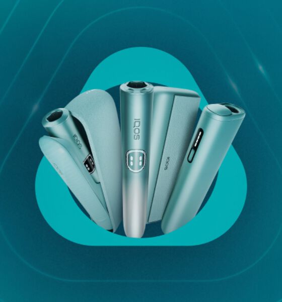 Line-up of IQOS ILUMA i Prime devices in teal with holders and cases, displayed against a turquoise background.