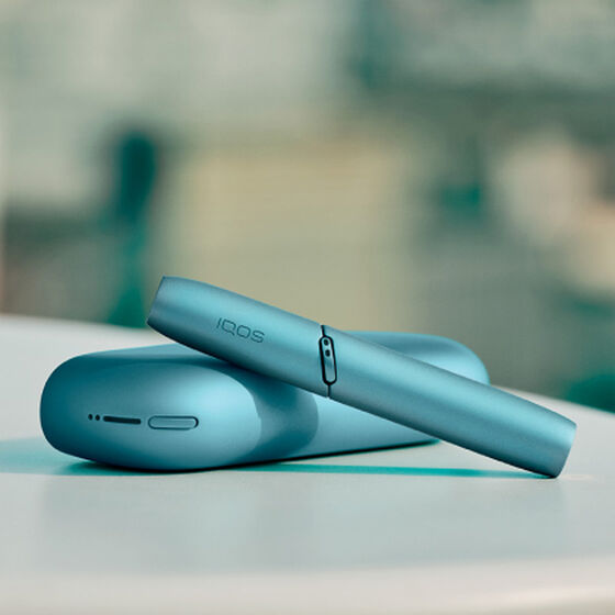 Turquoise IQOS Originals Duo holder and pocket charger on table.