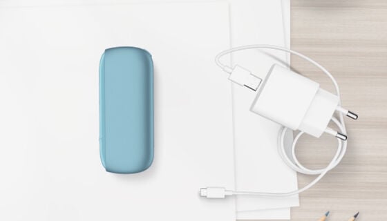 شاحن جيب جهاز IQOS ORIGINALS DUO بلون التركواز بجانب كابل الشحن.