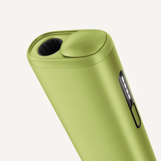 Close-up of the IQOS ILUMA i ONE device in a fresh lime-green finish, featuring the holder with a sleek button and LED indicator lights.