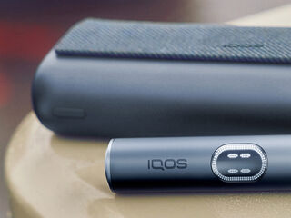 Hands holding smartphones and one IQOS device.