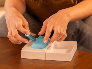 Hands unboxing an IQOS device.