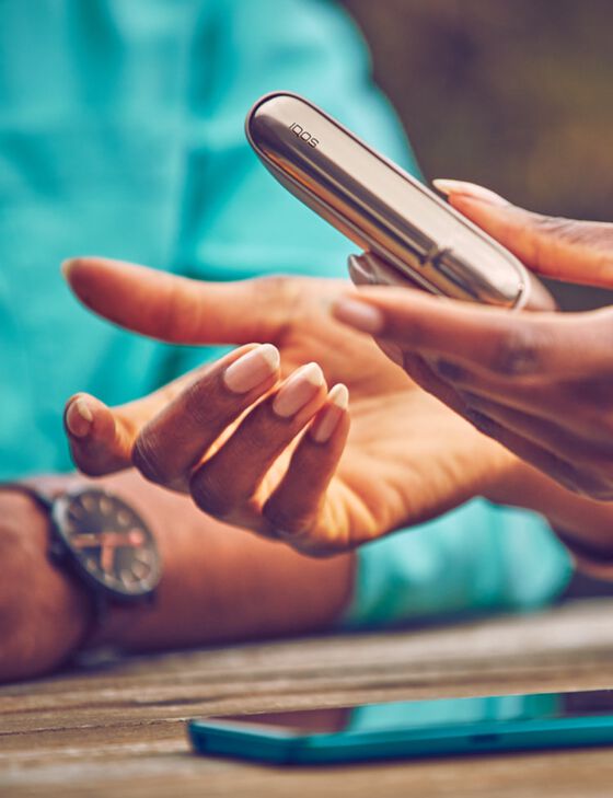 Close up of hands of two people in discussion; one holds a gold khaki ILUMA device.