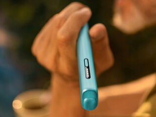 Hands holding smartphones and one IQOS device.