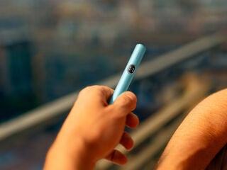 Two people holding phones over two cups of coffee.