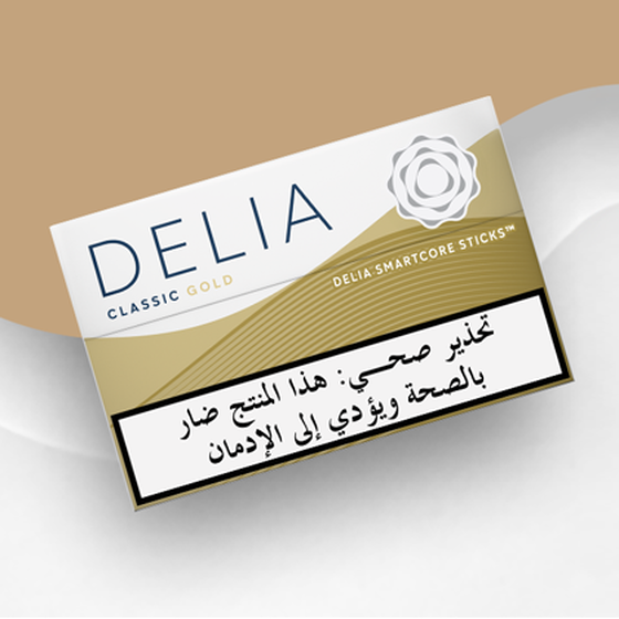 IQOS ILUMA DELIA Classic Gold tobacco sticks package on a wavy gold and white background