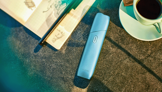 جهاز التبغ المُسخَّن IQOS Originals One بلون التركواز موضوع على طاولة.
