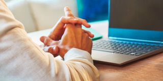 A man sitting on a couch looking at a laptop.