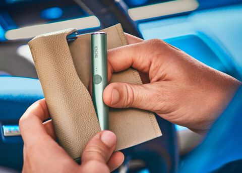 صورة مقربة ليد تحمل جهاز IQOS ILUMA باللون الأخضر.