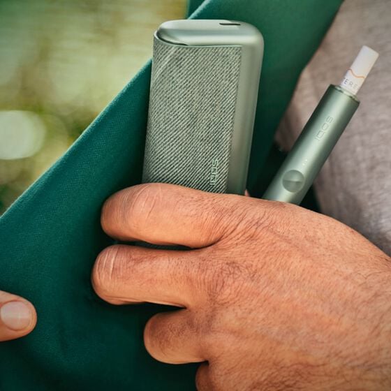 صورة مقربة ليد تخرج جهاز IQOS ILUMA من الجيب.