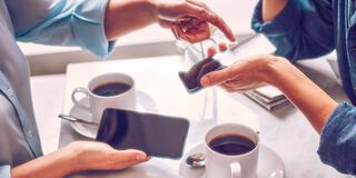 Two people holding phones over two cups of coffee.