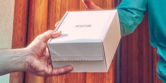 Someone handing over an IQOS box.
