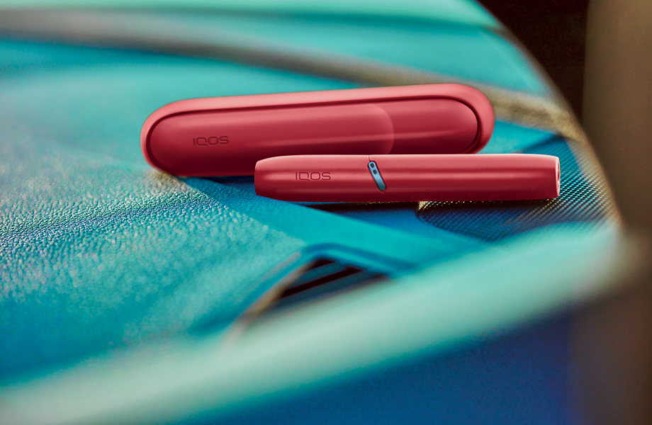 يدان تمسكان جهاز التبغ المُسخَّن IQOS Originals One بلون التركواز.