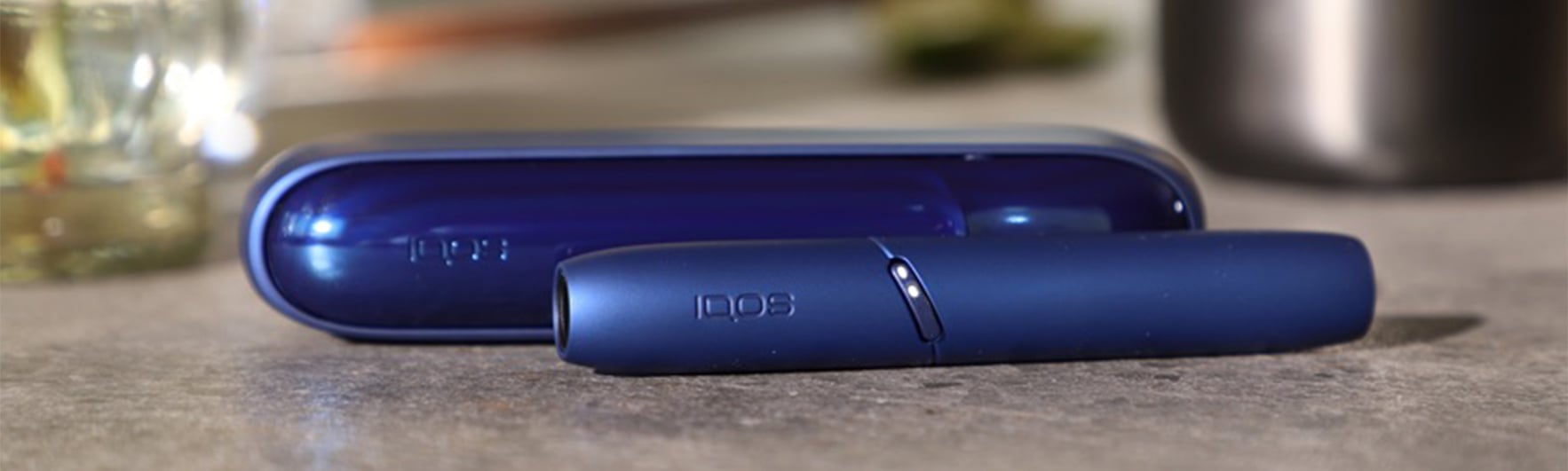 A blue IQOS and its cover lying on a table