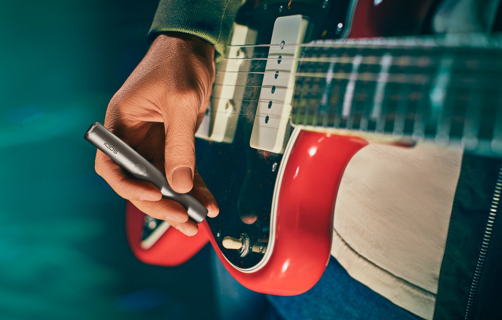 جهاز IQOS Originals One بلون التركواز موضوع على طاولة قهوة.