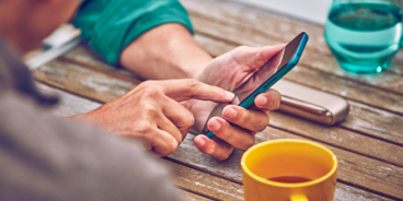 Man on a couch with his IQOS kit and the mobile in his hands